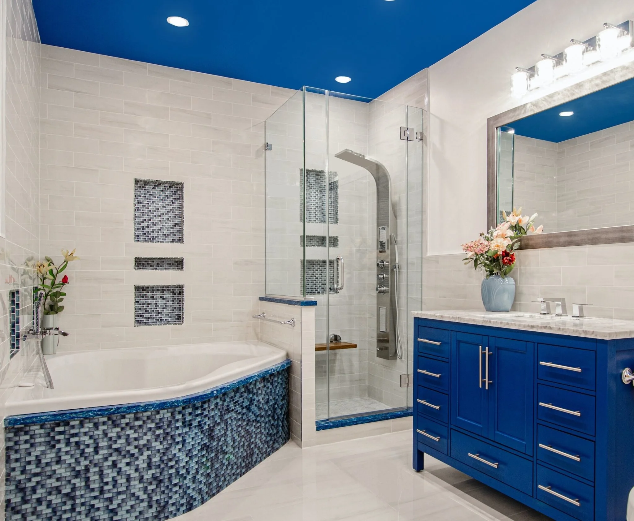 A bathroom featuring blue and white tiles, with a modern shower installed against the wall.