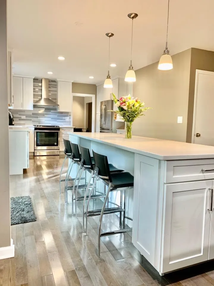 A kitchen with a central island and stools, evidence of a recent renovation.