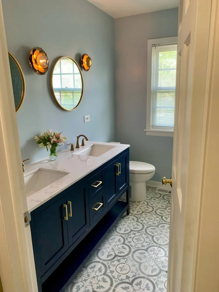 A remodeled bathroom featuring blue cabinets and white tile, showcasing a modern and stylish design.
