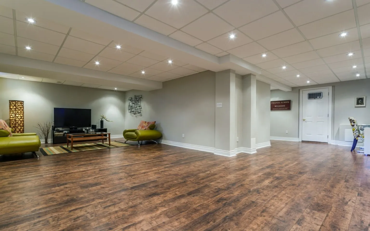 A cozy living room featuring hardwood floors and a television, showcasing a remodeled basement space.