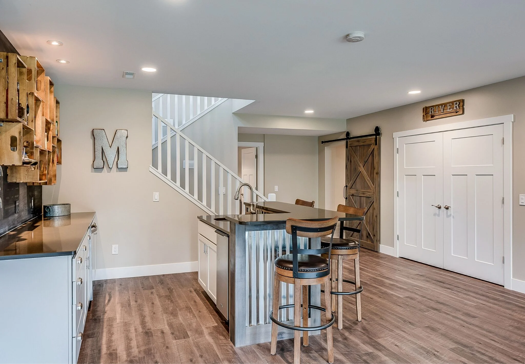 A spacious kitchen with a stylish bar and a staircase in the background.