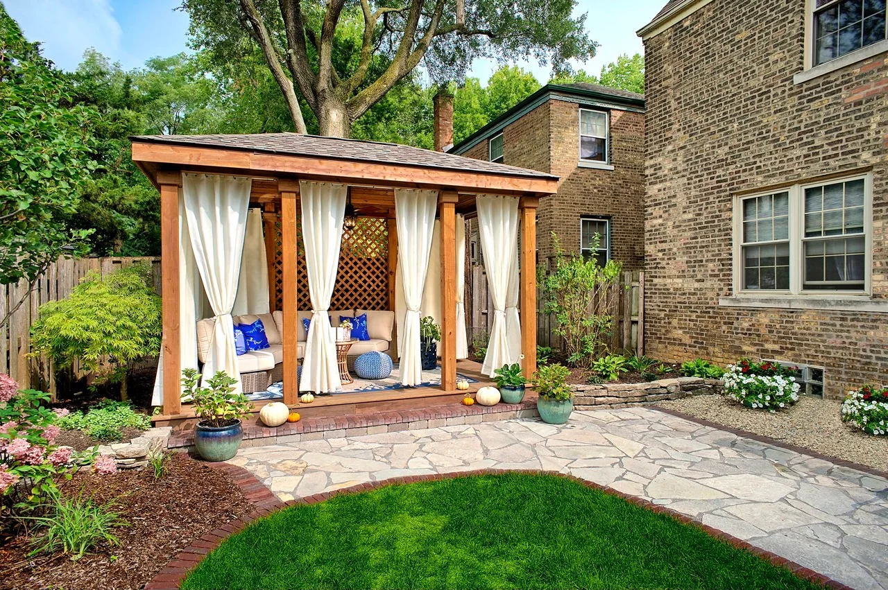 A charming gazebo adorned with curtains, featuring a spacious patio area for outdoor leisure and socializing.