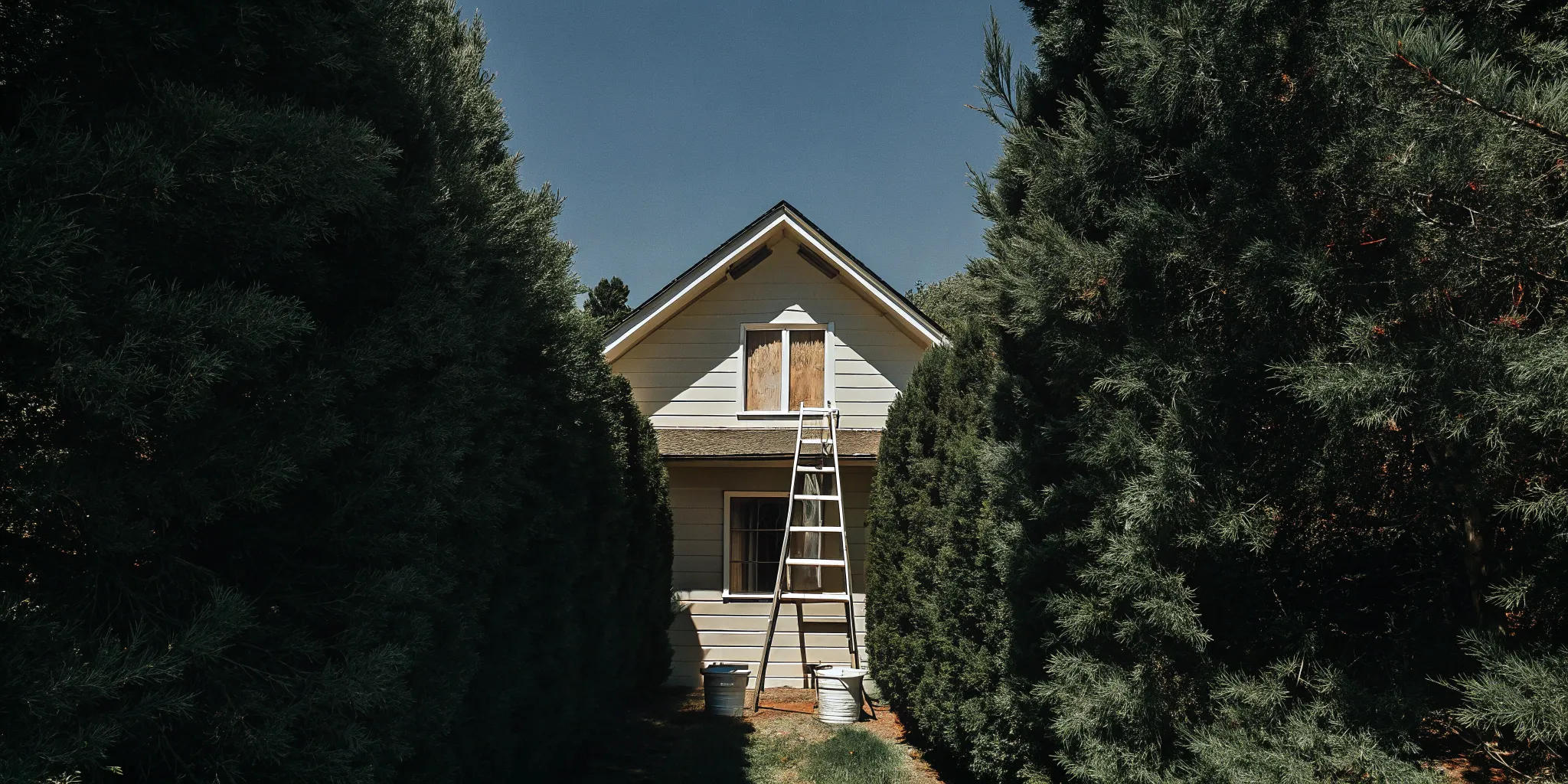 Painting contractor's ladder and equipment in front of a house ready for exterior painting.