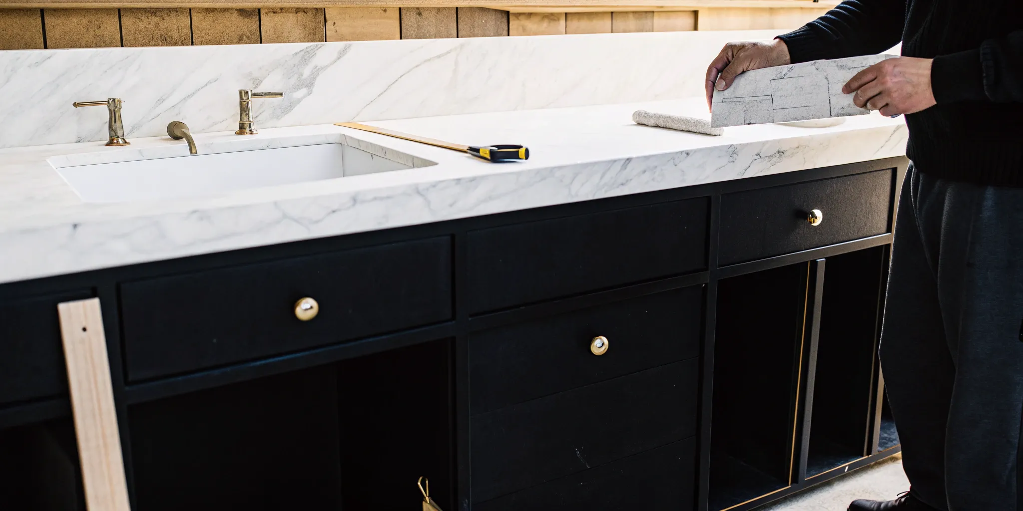 A general contractor measures a vanity countertop for a bathroom remodel.