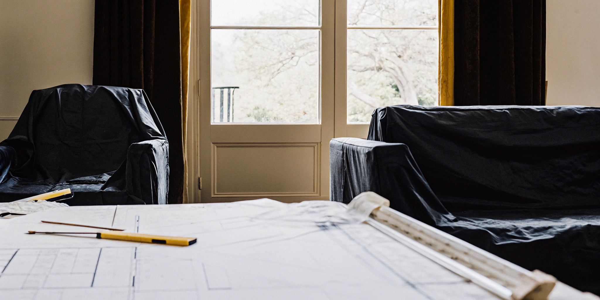 Planning the cost of a full home renovation with blueprints and tools in a living room.