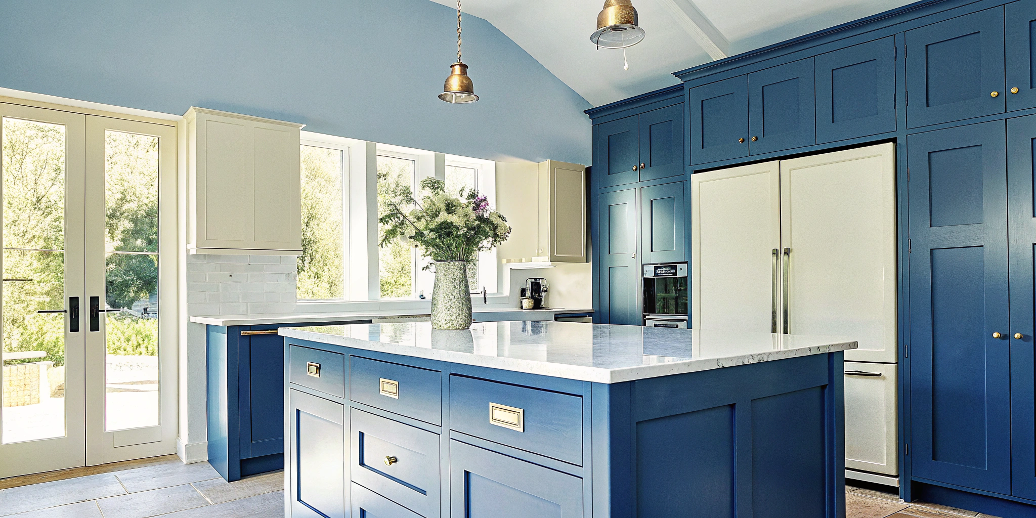 Modern Des Plaines kitchen remodeling with blue cabinets, white countertops, and large windows.